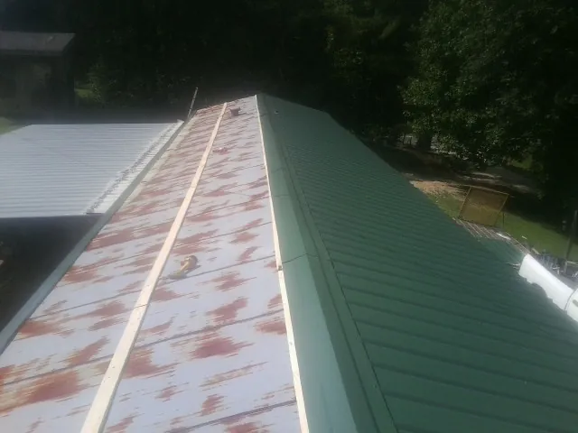 Old rusted panels beside newly installed green metal roofing — Wind Damage Roof Repair by Roofing Brothers in Shelby